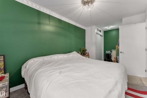 Bedroom featuring a statement green accent wall, decorative crown molding, and textured ceiling - 7 14115 82 Street, Edmonton, AB - Indoor Photo Showing Bedroom