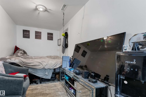 White-painted room featuring a single overhead light fixture, a ceiling vent, and a mirrored media console - 7 14115 82 Street, Edmonton, AB - Indoor Photo Showing Bedroom