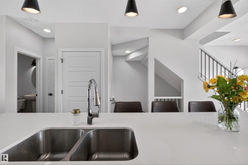 The kitchen features a double basin stainless steel sink with a chrome faucet, set within a light-colored countertop - 28 6214 Cartmell Crest, Edmonton, AB - Indoor Photo Showing Kitchen With Double Sink