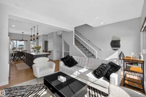 The living area features light hardwood flooring, light grey walls, and a staircase with white risers and black balusters - 28 6214 Cartmell Crest, Edmonton, AB - Indoor