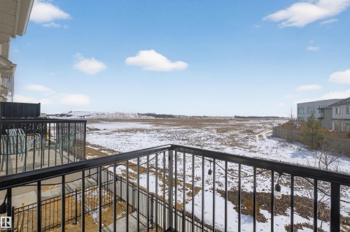 The property features a balcony with black railings, offering views of a snow-covered field and distant buildings under a clear sky - 28 6214 Cartmell Crest, Edmonton, AB - Outdoor With View