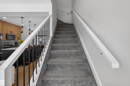 Carpeted staircase with white handrails and black balusters - 28 6214 Cartmell Crest, Edmonton, AB - Indoor Photo Showing Other Room