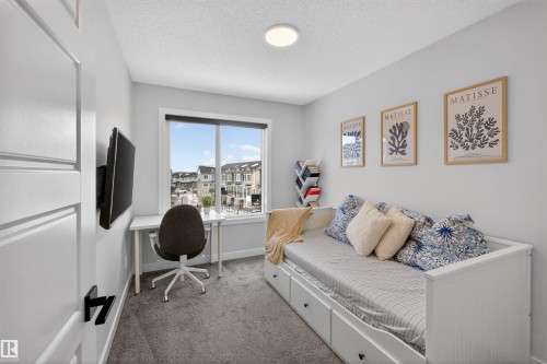 The room features light gray walls, a window overlooking residential properties, and a ceiling light fixture - 28 6214 Cartmell Crest, Edmonton, AB - Indoor