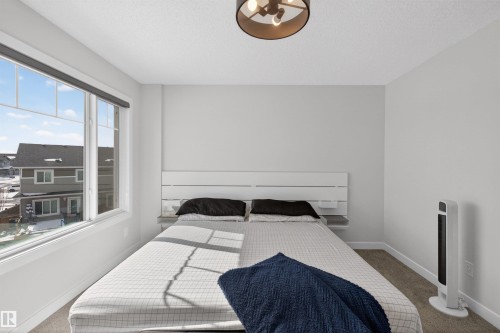 Bedroom with light grey walls, carpeted flooring, and a large window providing natural light - 28 6214 Cartmell Crest, Edmonton, AB - Indoor Photo Showing Bedroom