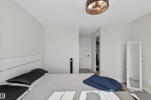 This room features light-colored walls, a modern ceiling light fixture, and carpeted flooring - 28 6214 Cartmell Crest, Edmonton, AB - Indoor Photo Showing Bedroom