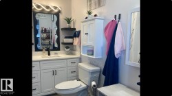 Modern bathroom featuring a white vanity with black hardware, a rectangular undermount sink, and a white countertop - 