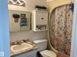Bathroom featuring a white vanity with a marble-finish countertop, a brass-finish faucet, and a wall-mounted mirrored medicine cabinet - 