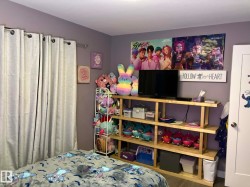 Room featuring light purple wall paint, light-colored window treatments, and a light wood-finish shelving unit - 