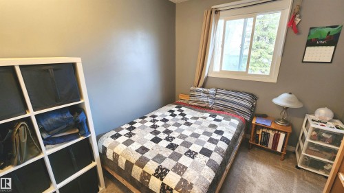 Carpeted room featuring a white-framed window, neutral wall paint, and a built-in white shelving unit - 3531 46 Street, Edmonton, AB - Indoor Photo Showing Bedroom