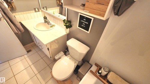 Bathroom featuring a vanity with an integrated sink, white tile flooring, and a wall-mounted mirror - 3531 46 Street, Edmonton, AB - Indoor Photo Showing Bathroom