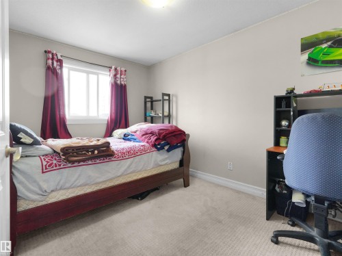 Bedroom featuring light-colored walls, carpeted flooring, a window with trim, and a ceiling light fixture - 5192 1B Avenue Sw, Edmonton, AB - Indoor Photo Showing Bedroom