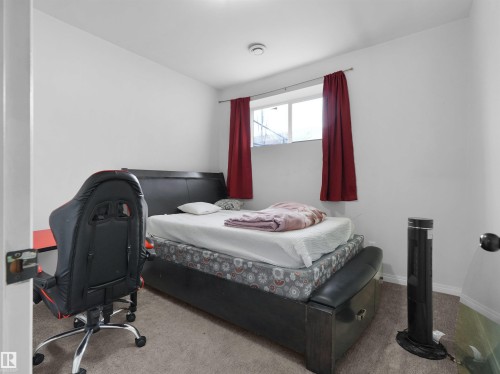Carpeted bedroom with a single window, white walls, and a ceiling-mounted smoke detector - 5192 1B Avenue Sw, Edmonton, AB - Indoor Photo Showing Bedroom