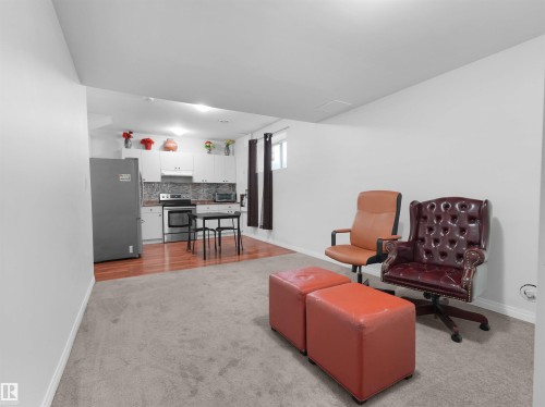 Open-concept living space featuring light gray carpeting and a kitchen area with wood-finish flooring - 5192 1B Avenue Sw, Edmonton, AB - Indoor