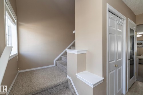 Carpeted staircase featuring white trim, a window with blinds, and neutral wall tones - 50 14803 Miller Boulevard, Edmonton, AB - Indoor Photo Showing Other Room