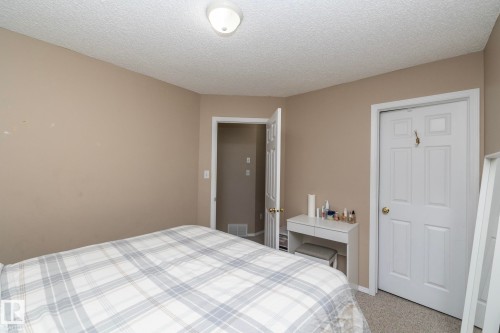 Neutral tone wall paint, textured ceiling finish, and ceiling-mounted light fixture - 50 14803 Miller Boulevard, Edmonton, AB - Indoor Photo Showing Bedroom