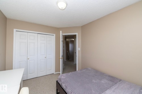 Room featuring a textured ceiling, neutral wall paint, and light-colored carpet flooring - 50 14803 Miller Boulevard, Edmonton, AB - Indoor Photo Showing Bedroom