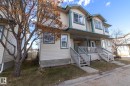 Multi-level townhouse exterior featuring light-colored siding with contrasting trim, multiple gabled dormers, a covered entryway with a porch, and dual exterior staircases - 50 14803 Miller Boulevard, Edmonton, AB  - Outdoor 