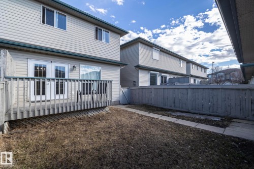 Rear exterior featuring a wooden deck with railing, double glass-paneled patio doors, and light-colored siding - 50 14803 Miller Boulevard, Edmonton, AB - Outdoor With Deck Patio Veranda