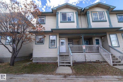 Multi-level exterior featuring light-toned horizontal siding, contrasting darker trim, pitched gables, and multiple windows - 50 14803 Miller Boulevard, Edmonton, AB - Outdoor With Deck Patio Veranda With Facade