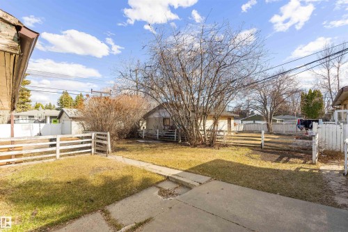 Expansive backyard featuring a partial white picket fence, mature trees, and a concrete pathway - 9007 149 Street, Edmonton, AB - Outdoor