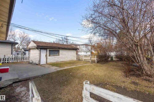 Detached garage building featuring white siding and a shingled roof, accompanied by a concrete patio area - 9007 149 Street, Edmonton, AB - Outdoor
