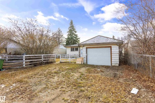 Detached garage with a paneled white door, white siding, and a sloped roof - 9007 149 Street, Edmonton, AB - Outdoor