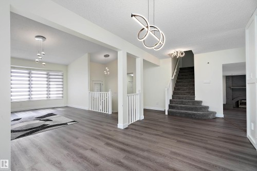 The property features modern plank flooring, a staircase with carpeted treads, and contemporary light fixtures - 11020 158 Avenue, Edmonton, AB - Indoor Photo Showing Other Room