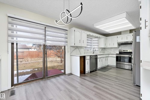The kitchen features white cabinetry, stainless steel appliances, and light-toned countertops with a matching backsplash - 11020 158 Avenue, Edmonton, AB - Indoor Photo Showing Kitchen