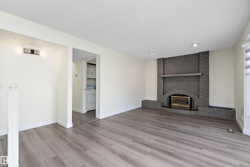 Living area featuring wood-look flooring, a brick fireplace with a mantel, and recessed lighting - 11020 158 Avenue, Edmonton, AB - Indoor With Fireplace