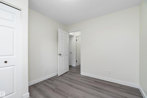 This room features light gray wood-style flooring and white walls, creating a bright and neutral palette - 11020 158 Avenue, Edmonton, AB - Indoor Photo Showing Other Room