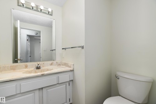 Bathroom featuring a vanity with a light-colored countertop, an integrated sink, and a mirror with overhead lighting - 11020 158 Avenue, Edmonton, AB - Indoor Photo Showing Bathroom