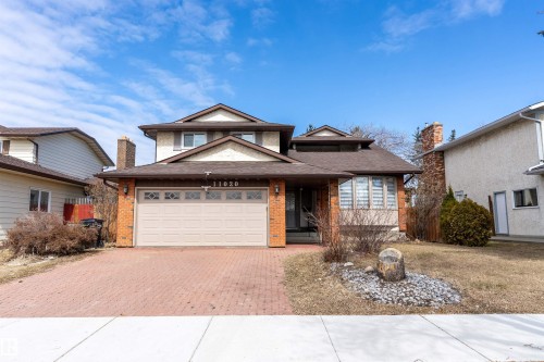 The property features a brick facade, a paved driveway, and an integrated garage - 11020 158 Avenue, Edmonton, AB - Outdoor With Facade