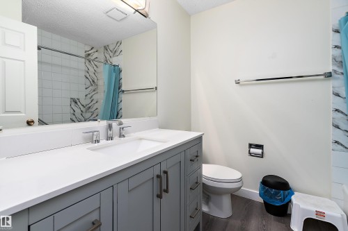 This bathroom features a contemporary vanity with a spacious white countertop, a mirror, and a toilet - 11020 158 Avenue, Edmonton, AB - Indoor Photo Showing Bathroom