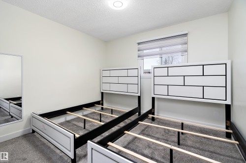 This bedroom features light-colored walls, a window with blinds, and a textured ceiling - 11020 158 Avenue, Edmonton, AB - Indoor