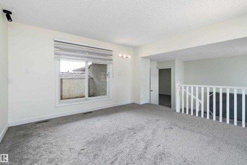 This bright space features light-colored walls, soft gray carpeting, and a window with blinds, allowing for natural light - 11020 158 Avenue, Edmonton, AB - Indoor