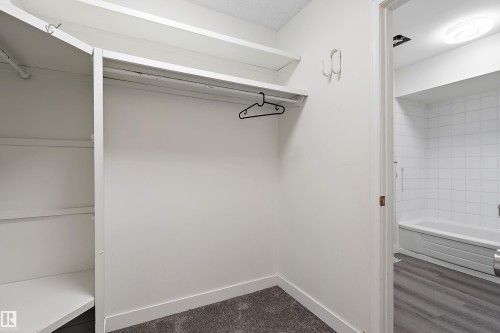 The property features a closet with shelving and a hanging rod, as well as a bathroom with a tiled shower and bathtub - 11020 158 Avenue, Edmonton, AB - Indoor With Storage