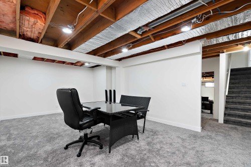 Spacious room featuring light grey carpeting, white walls, and exposed wooden ceiling beams - 11020 158 Avenue, Edmonton, AB - Indoor Photo Showing Basement