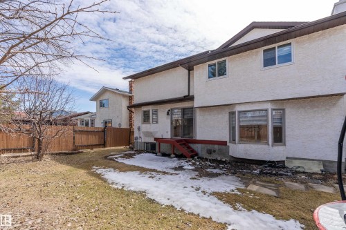 The property features a stucco exterior, a fenced yard, and a deck with red stairs - 11020 158 Avenue, Edmonton, AB - Outdoor