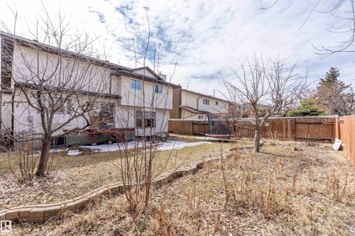 The property features a fenced yard, a rear deck, and mature trees - 11020 158 Avenue, Edmonton, AB - Outdoor