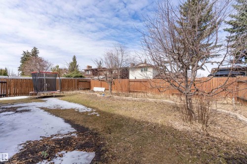 The property features a fenced yard with a combination of grass and bare ground, along with several trees - 11020 158 Avenue, Edmonton, AB - Outdoor