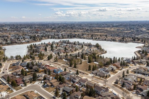 Aerial view showcasing the property's location within a residential area, featuring a large body of water with some ice cover, surrounded by numerous homes and mature trees - 11020 158 Avenue, Edmonton, AB - Outdoor With Body Of Water With View