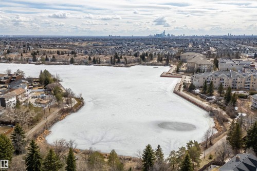Aerial view of the property's surrounding area, featuring a large frozen body of water, residential properties, and distant urban skyline - 11020 158 Avenue, Edmonton, AB - Outdoor With Body Of Water With View