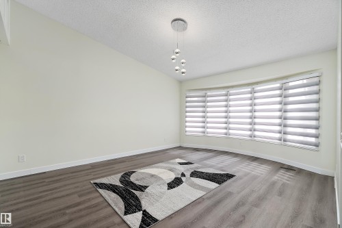 This room features hard surface flooring, a large bay window with blinds, and a contemporary ceiling light fixture - 11020 158 Avenue, Edmonton, AB - Indoor Photo Showing Other Room