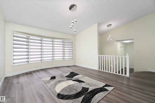 This room features light-colored walls, wood-style flooring, and a large bay window with blinds - 11020 158 Avenue, Edmonton, AB - Indoor