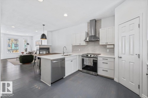 Kitchen featuring white cabinetry, stainless steel appliances, and white tile backsplash - 8737 83 Avenue, Edmonton, AB - Indoor Photo Showing Kitchen With Upgraded Kitchen