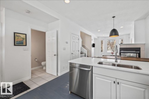 The kitchen features a double basin sink, stainless steel dishwasher, white cabinetry, and a white countertop - 8737 83 Avenue, Edmonton, AB - Indoor Photo Showing Kitchen With Double Sink