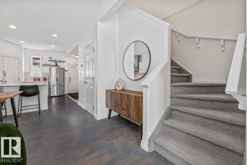 The property features a white kitchen with a stainless steel refrigerator, and a carpeted staircase with a white banister - 8737 83 Avenue, Edmonton, AB - Indoor Photo Showing Other Room