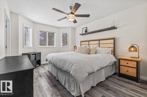 The room features durable flooring, a ceiling fan with integrated lighting, and multiple windows that provide natural light - 8737 83 Avenue, Edmonton, AB - Indoor Photo Showing Bedroom