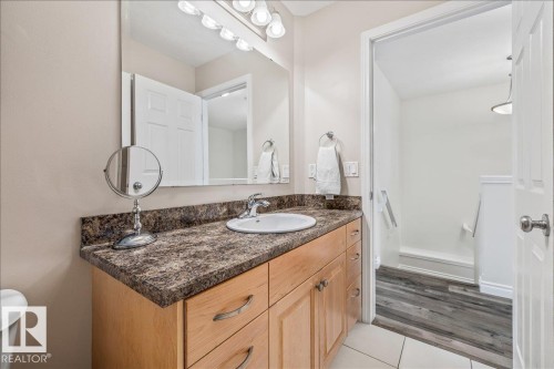 Bathroom vanity featuring a countertop with an integrated sink, a large mirror, and light wood cabinetry with drawers and storage - 8737 83 Avenue, Edmonton, AB - Indoor Photo Showing Bathroom