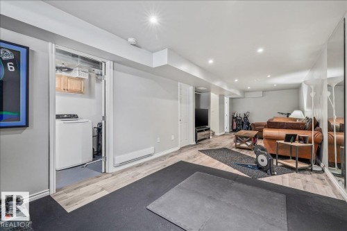 This versatile lower level features recessed lighting, light-toned flooring, and a dedicated laundry area with a white washing machine and overhead cabinetry - 8737 83 Avenue, Edmonton, AB - Indoor Photo Showing Other Room